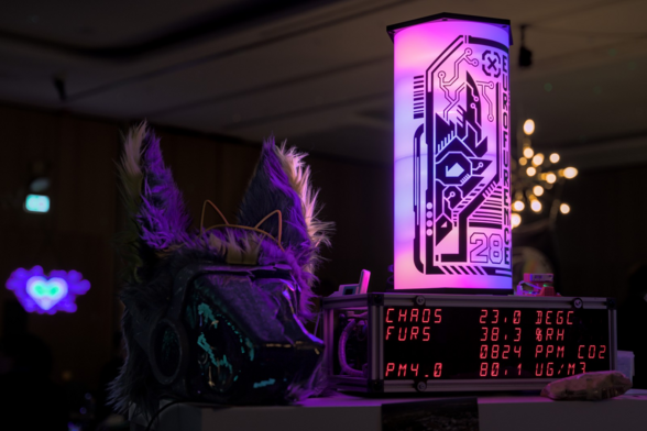 A protogen head sitting on a table next to a display showing air quality data and date