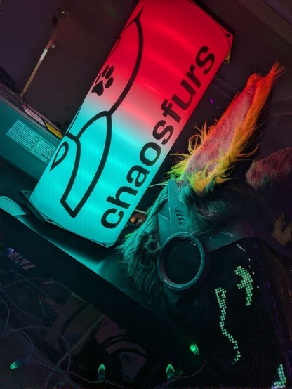 A protogen fursuit head next to a RGB lamp showing a fairydust^W furrydust and "chaosfurs"