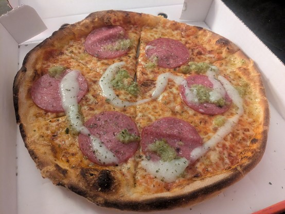 Salami pizza with some streaks of white garlic sauce