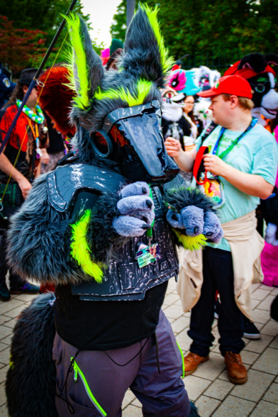A grey and yellow protogen fursuit at a fursuit parade