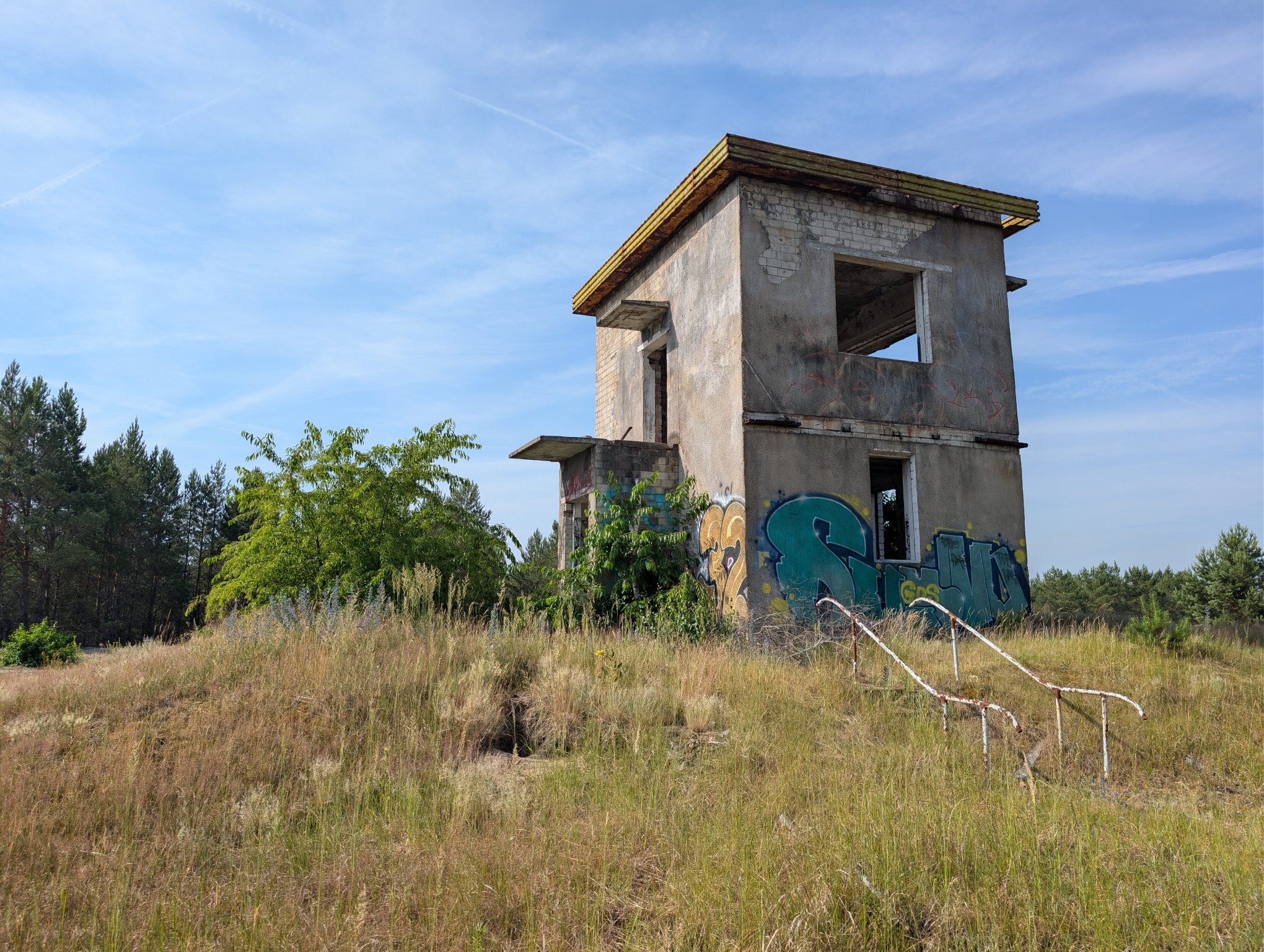 A small abandoned watch tower building in the middle of a grassy, dry landscape