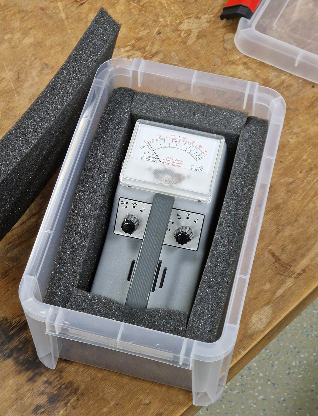 Photo of a 1970s Geiger counter in a plastic box that has been padded with foam cutouts to make a perfect surround for it.