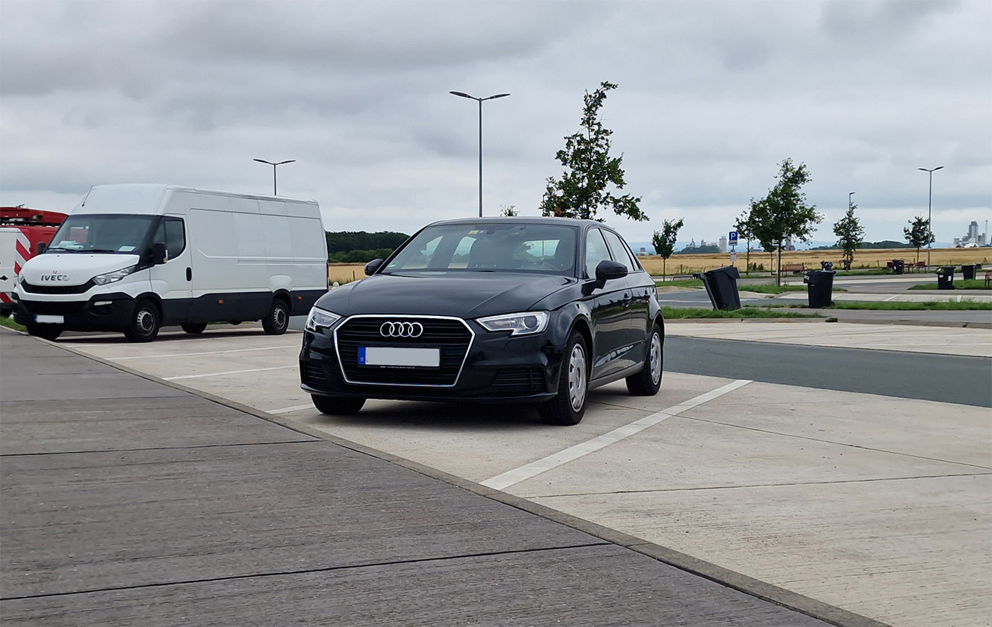 Photo of a humble automobile parked at a rest area somewhere in the middle of nowhere on a gloomy and overcast day.