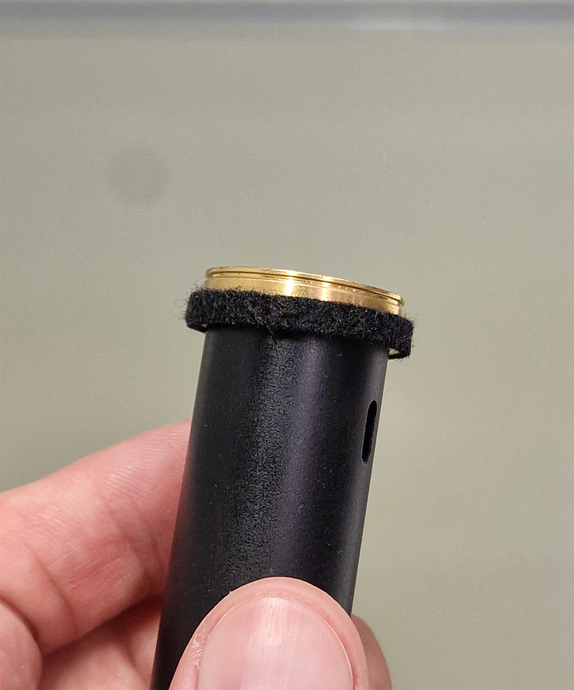 Close up photo of the top of a VSM detection coilset, with a black strip of fuzz being perfectly attached around its circumference. This humble part serves an important purpose of keeping this thing perfectly centered in the sample chamber, thus allowing me to grab it with a special tool via the groove above it. I always diligently replaced these when they became damaged or detached, and recently learned that it can cause issues if they're missing and the removal tool fails to slide over the top. I'm the only one who takes care of this tiny little detail, and I of course don't just get shit from a hardware store but always buy the tiny satchel of overpriced felt strips by the manufacturer. You wouldn't do botch jobs on your classic car either, would you? You want the original parts, yes you do.